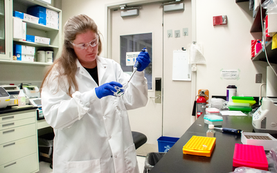 Researcher working in lab with safety glasses and gloves