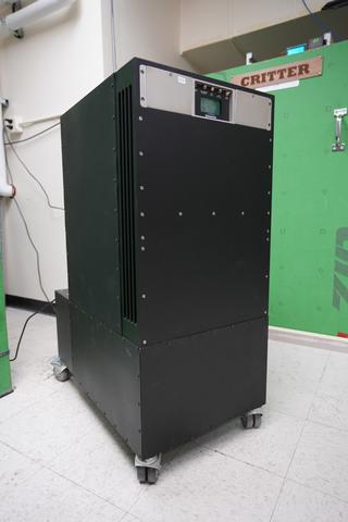 A rectangular black cabinet on wheels has a few switches and a small screen near the top. 