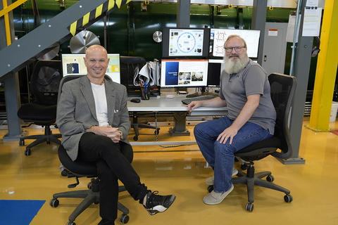 NIST researchers sit in chairs next to each other at NIST's Gaithersburg campus, with computers and technical equipment in the background.