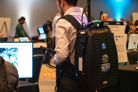 PSCR staff member with lidar backpack on in demo hall at 5x5