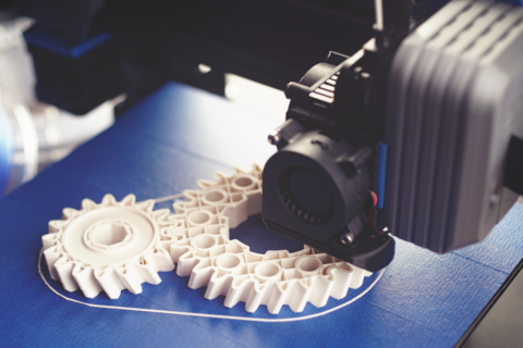 a 3D printer prints white gears using polymer filament