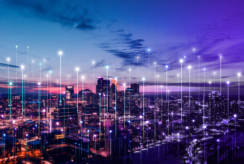 Stylized network connection points rise above a city skyline at sunset.
