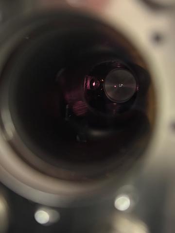 View through a circular opening into a dark interior. A red dot floats in the darkness. 
