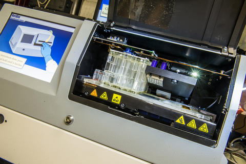 A photo of a rapid DNA typing instrument.  A screen controls the interface and a chip is loaded into the instrument. 