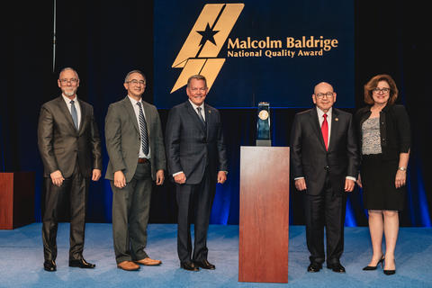 Chickasaw Nation Department of Health standing beside their 2024 Baldrige Award Crystal.