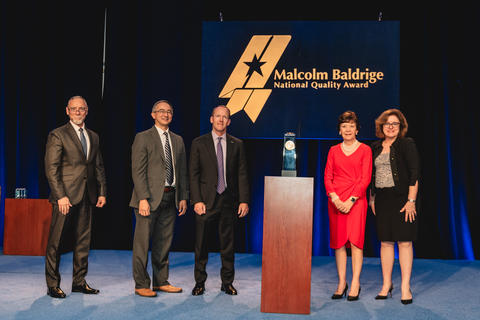 Freese and Nichols, Inc. standing beside their 2024 Baldrige Award Crystal.