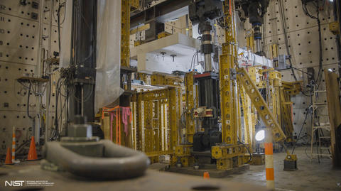 Horizontal concrete slab is visible in a forest of scaffolding and equipment in a large indoor space. 