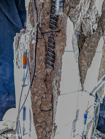 Close-up view of vertical fissures and exposed rebar in test column with sensors and markers still attached. 