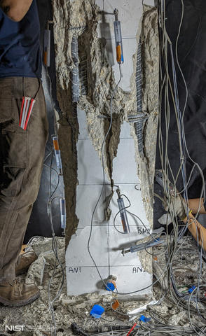 A vertical column with sensors attached has shredded-looking cracks and broken parts. 