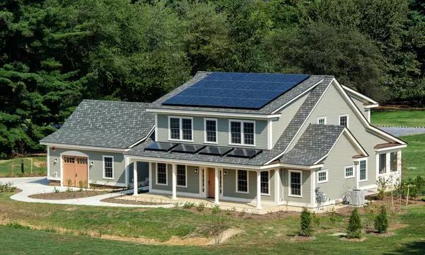 Photograph of large residential-style home with blue tile roof and solar panel in suburban campus setting.