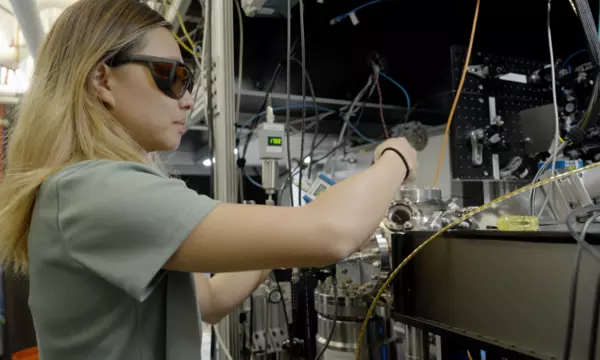 Sun Park wears safety glasses as she adjusts wiring and equipment in the lab. 