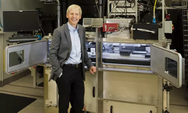 NIST Chief Metrologist Jim Olthoff stands in front of equipment in a lab. 