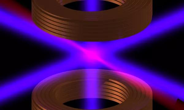 Laser light in pink and purple crosses between two cylindrical shapes on a black background. 