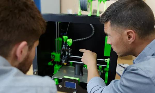 two researchers work at a 3D printer