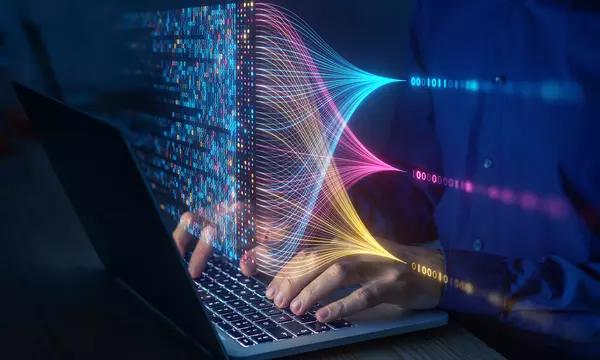 Hands rest on a laptop keyboard beneath a floating overlay of computer code and connecting lines.