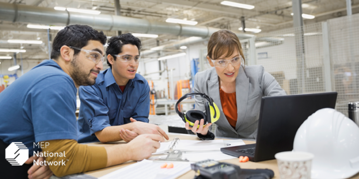 manufacturing team in a factory looking at a laptop