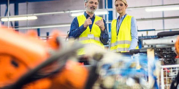 people looking at robots in action in a manufacturing facility