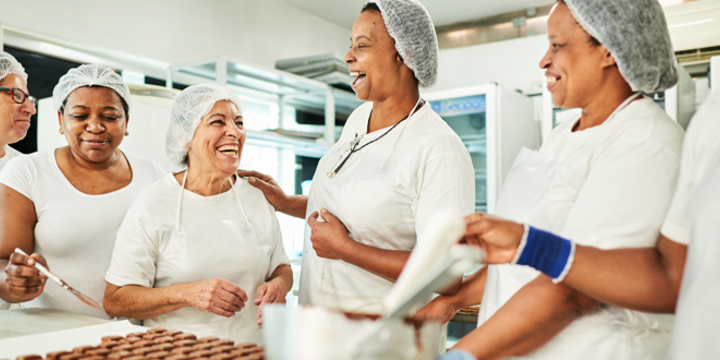 Group of confectioners laughing together while working in a chocolate factory