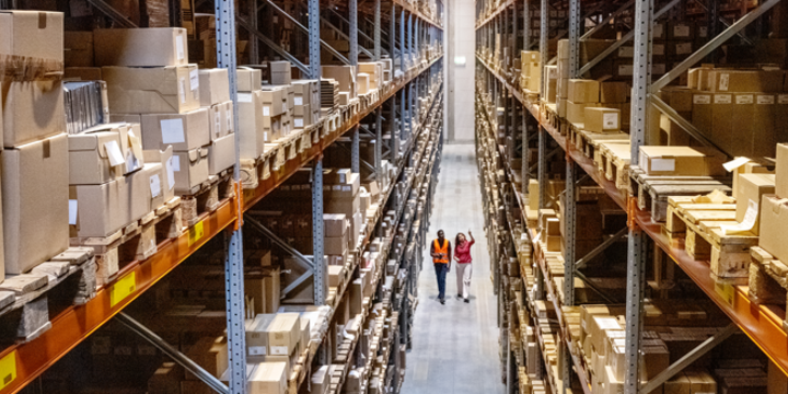 High angle view of a warehouse manager walking with foremen checking stock on racks