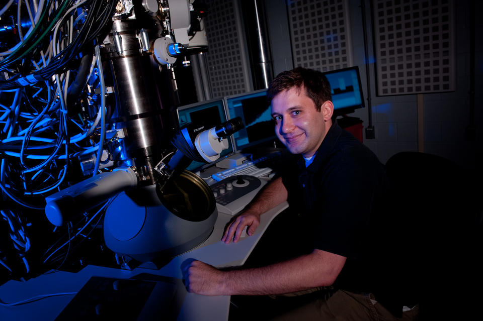 Ryan M. White sitting next to a microscope