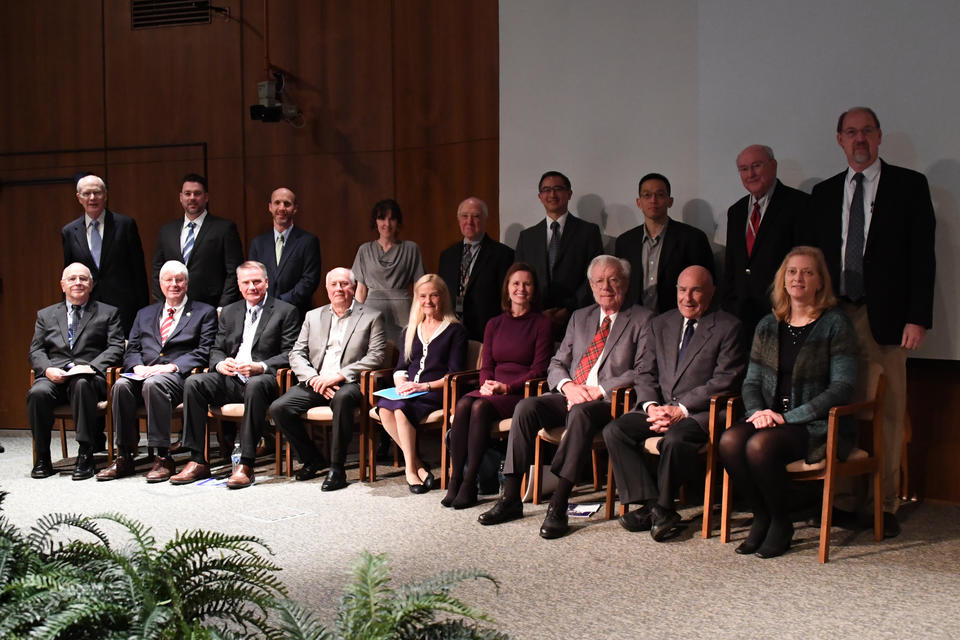 6 men and 3 women seated in front, 1 woman and 8 men standing behind