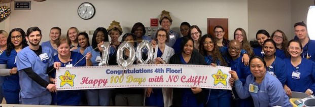 Duke Raleigh Hospital staff showing a sign that says celebrate 100 days with no instances of the hospital-acquired infection Clostridium difficile, also known as C.diff.
