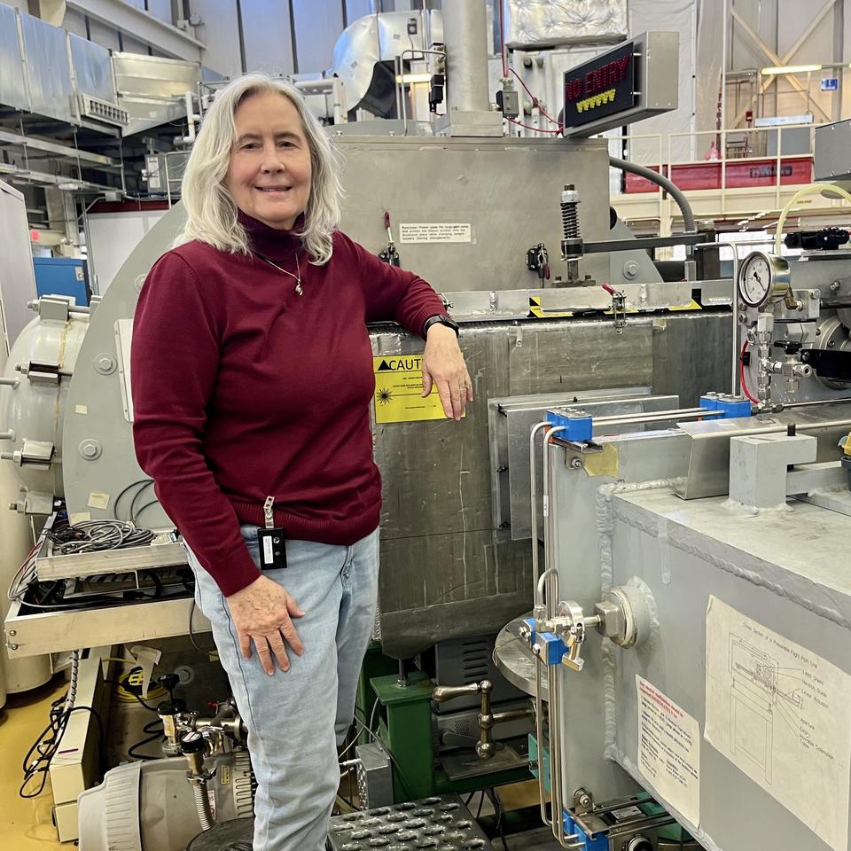 Susan Krueger poses in the lab, resting one arm on a large piece of scientific equipment. 