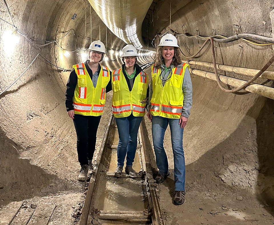 Freese and Nichols, Inc. photo showing three women employees with construction hats and vests standing in an intake tunnel.