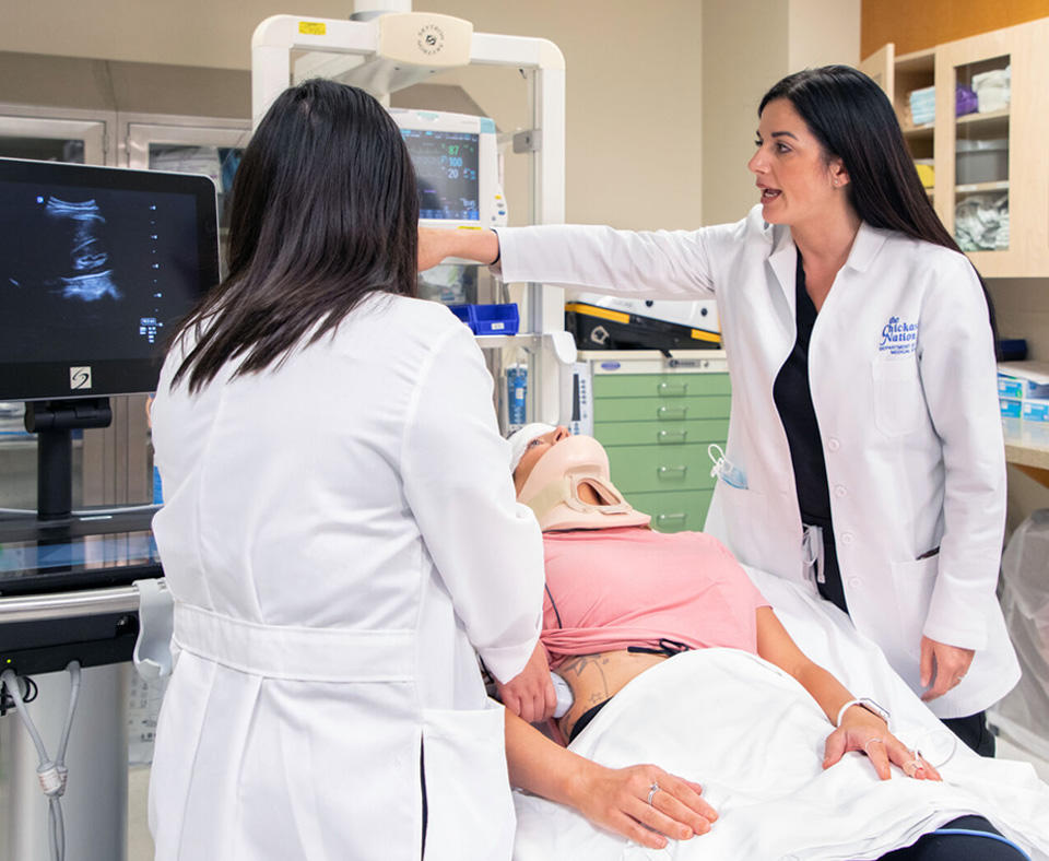 Chickasaw Nation Department of Health residency photo two female doctors discussing an ultrasound of the patient lying in the hospital bed.