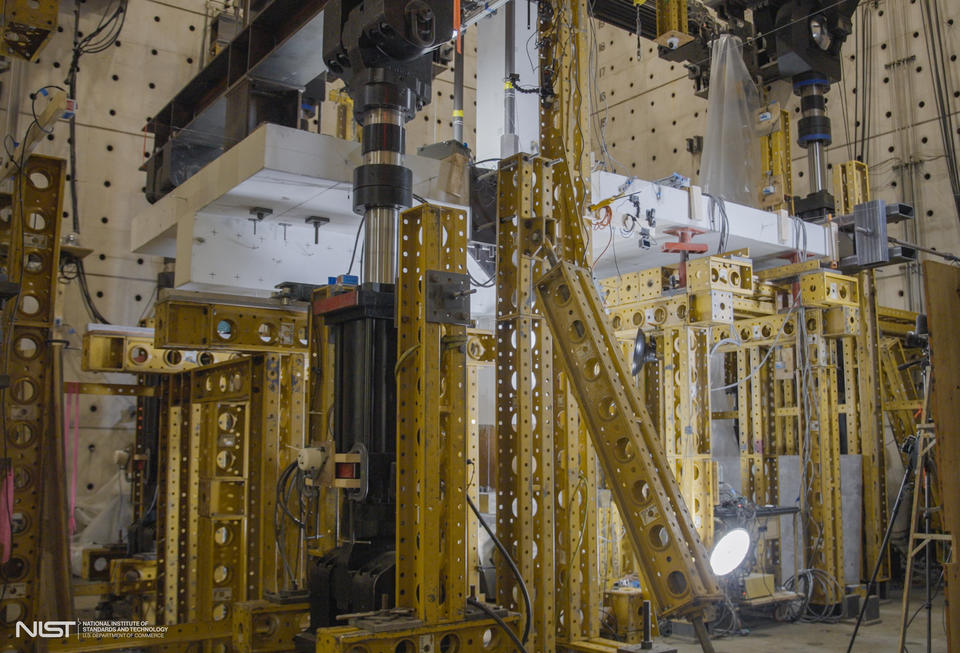 Horizontal concrete slab is visible in a forest of scaffolding and equipment in a large indoor space. 