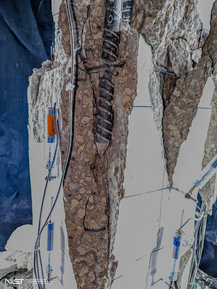 Close-up view of vertical fissures and exposed rebar in test column with sensors and markers still attached. 