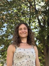 Esther Baumann poses outdoors with trees in the background.