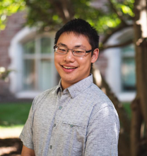 Ephraim Gau poses smiling for a head shot outdoors.