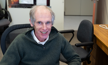 Alexander Kramida smiles for a portrait sitting at his desk.