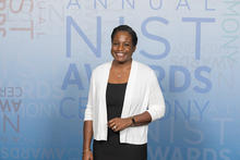 Melissa Taylor poses smiling in front of a banner for the NIST Awards Ceremony.