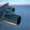 Closeup of a plane's jet engine as it flies above the clouds.