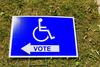 A polling station sign depicts an icon of a person in a wheelchair above the word "vote."