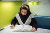 Kathryn Miller sits reading a book at a small table in the NIST library. 