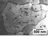 A black and white image of the aluminum alloy under a microscope. Most of the image is light grey, but there are many small black spots that have lines extending out from them like cracks.