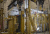 Horizontal concrete slab is visible in a forest of scaffolding and equipment in a large indoor space. 